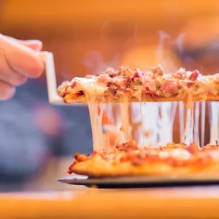 a person taking a slice of pizza