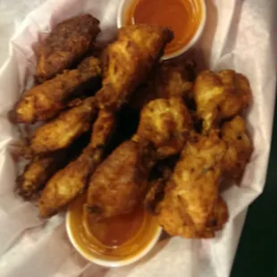 a basket of fried chicken wings with dipping sauce