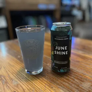 a can of june shine next to a glass of water