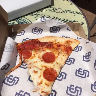 a slice of pepperoni pizza in a box