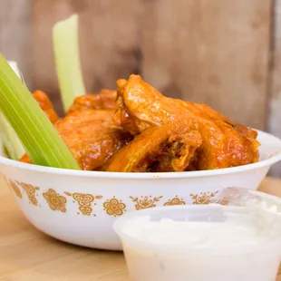 a bowl of buffalo wings with celery and ranch dressing