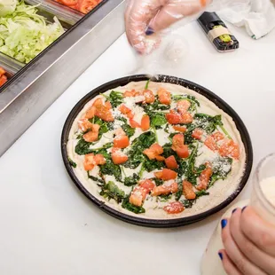 a person preparing a pizza in a kitchen
