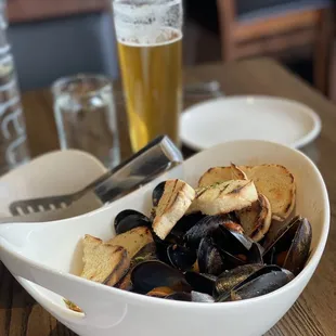 a bowl of mussels and a glass of beer