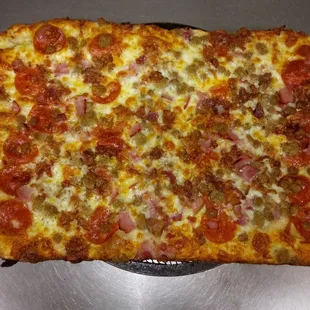 a square pizza with pepperoni, sausage, and cheese