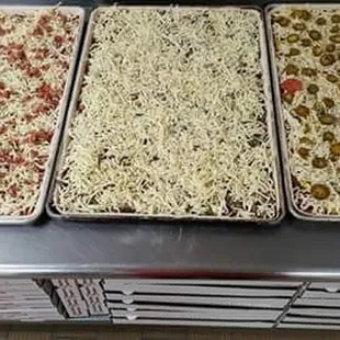 four pans of pizza on a counter