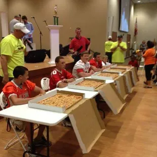 a large group of children sitting at tables with pizzas on them