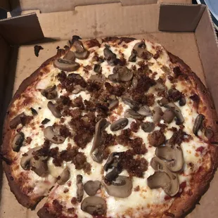 Cauliflower crust pizza with red sauce, sausage and mushrooms.