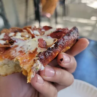 a hand holding a slice of pizza