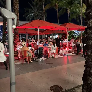 a crowd of people sitting under red umbrellas