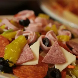 a plate of pepperoni, cheese, olives, and pepperoni