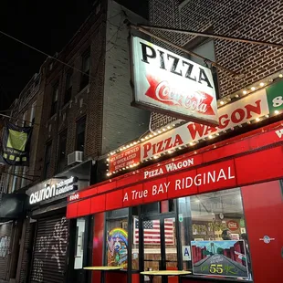 a woman walking past a pizza shop