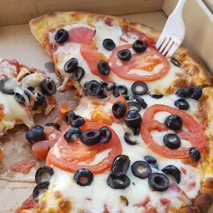 a slice of pizza with olives and tomatoes