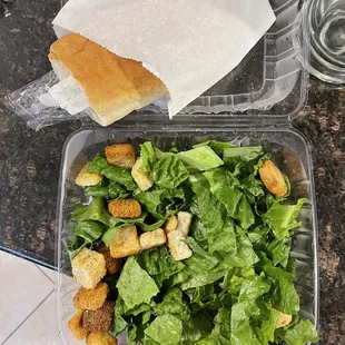 Caesar salad, fork and knife are inside this weird sub roll bread. Why even give bread? No one is eating that i promise you.