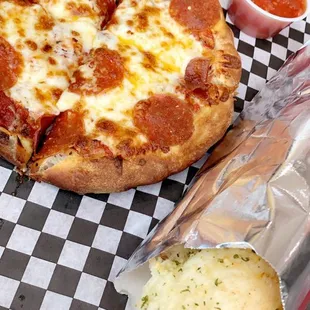 a slice of pepperoni pizza on a checkered tray