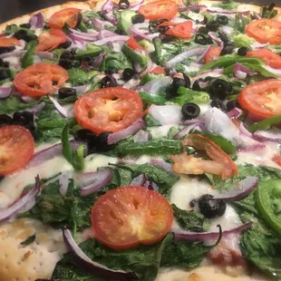 a pizza with tomatoes, onions, and spinach