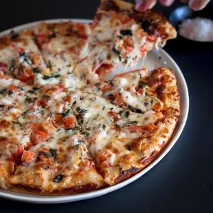 a person taking a slice of pizza