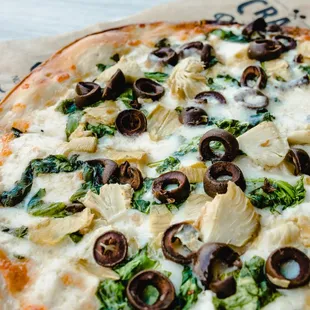 a pizza with olives and spinach