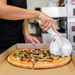 a person cutting a pizza