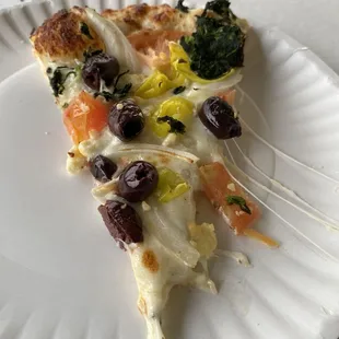 A slice of the Greek pizza. It&apos;s a white pizza with no tomato sauce.