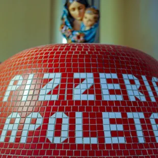 a red mosaic ball with the word pizzeria written on it