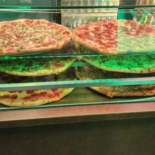 two pizzas in a display case