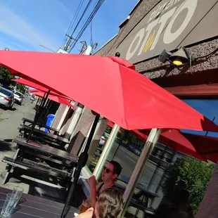 a man and a woman sitting under a red umbrella