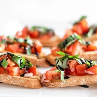 four pieces of bread topped with tomatoes and basil