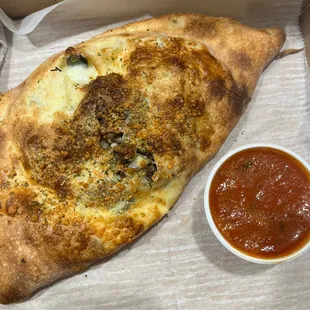 Calzone with veggies. Cooked well and good amount of filling. Served with small cup of sauce.