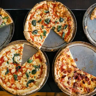 a variety of pizzas on pans