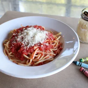 a bowl of spaghetti with sauce and crayons