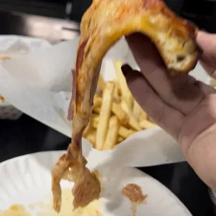 a hand holding a piece of pizza