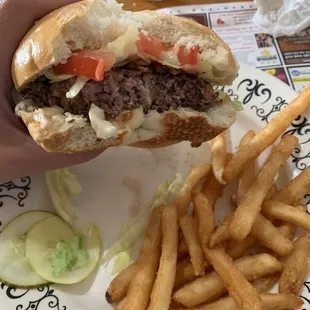 a hand holding a hamburger and french fries
