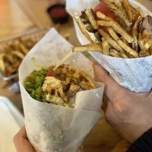 a person holding a sandwich and french fries
