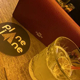 a glass of lemonade next to a red purse