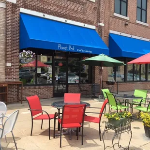 View of the café from the outdoor patio.  Shaded seating, flowers, a bike rack and lots of sun.