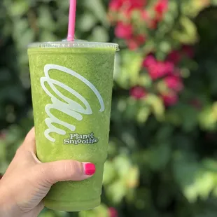 a hand holding a green smoothie