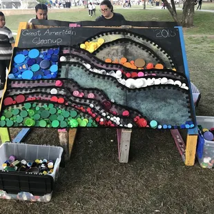 Interactive art piece made from recycled material - people are invited to place colored plastic lids into the picture.