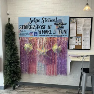 a tree and a sign in front of a white brick wall