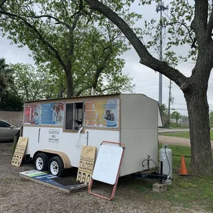 a food truck parked next to a tree