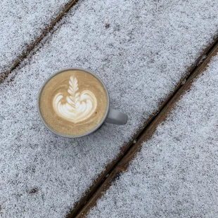 a cup of coffee on a table covered in snow