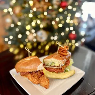 two sandwiches on a plate with a christmas tree in the background
