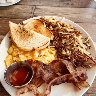 Scrambled eggs with cheddar cheese, toast, crispy real hash browns, thick bacon and ketchup.