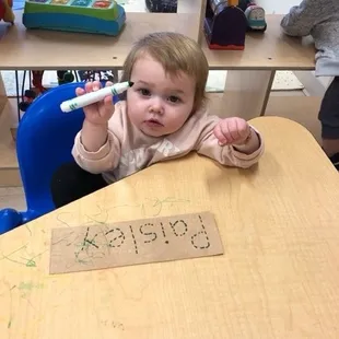 Coloring at school and learning the letters of her name