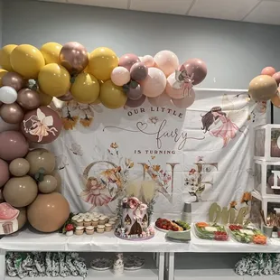 a table with balloons and cupcakes