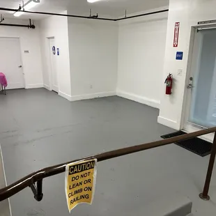 &quot;small party room&quot; with brown pipes/railings, hallway to the bathroom, staff room, and emergency exit at the back of the building