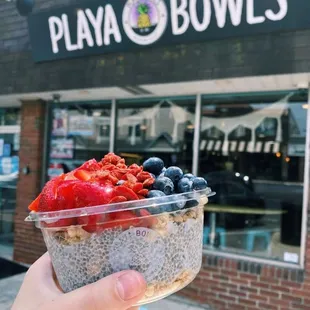 a hand holding a bowl of fruit