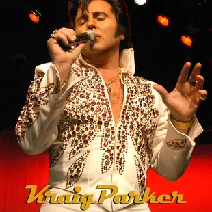 a man in a white suit singing into a microphone