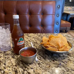 a bowl of chips and a bottle of salsa