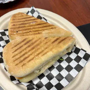 a grilled sandwich on a checkered paper plate