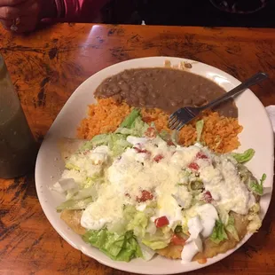 Chalupa stuffed with chicken topped with sour cream rice and refried beans on the side